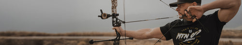 man wearing mtn ops shirt shooting an arrow